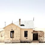 Beautiful Shot Of An Old Abandoned House In The Middle Of A Desert Near A Leafless Tree