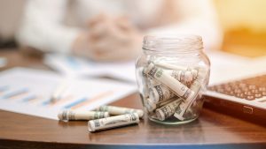 A Jar With Rolled Banknotes On The Table
