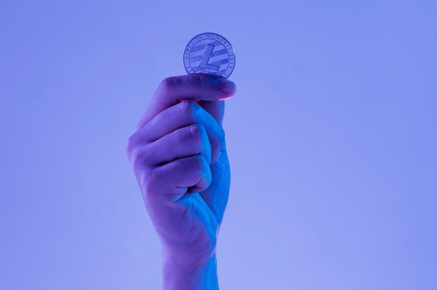 Male Hand With Golden Litecoin On Blue Background