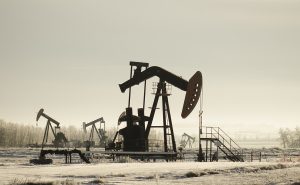 Field With Oil Pump Jacks Surrounded By Greenery Under Sunlight