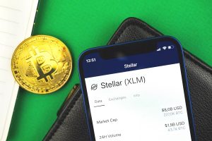 Stellar Xlm Crypto Currency Close Up Logo On The Screen Of Mobile Phone, Bitcoin On Office Desk, Business Workspace Background, Top View Photo